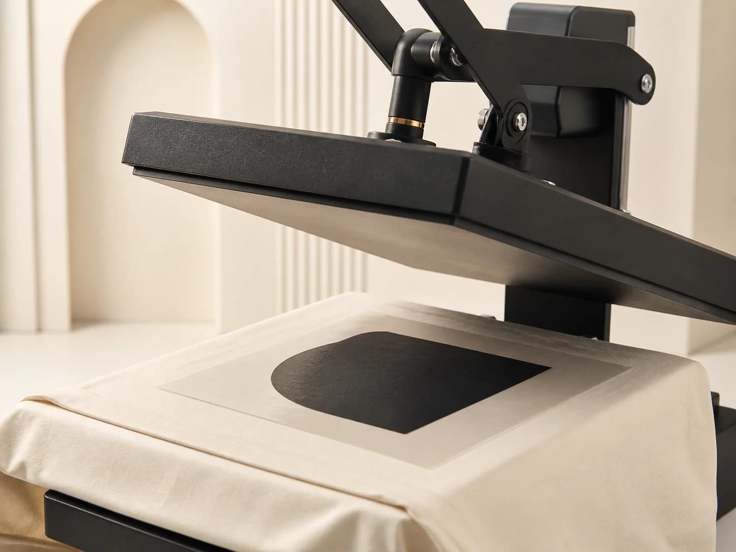 Heat-transfer press applying a black graphic shape to cream fabric